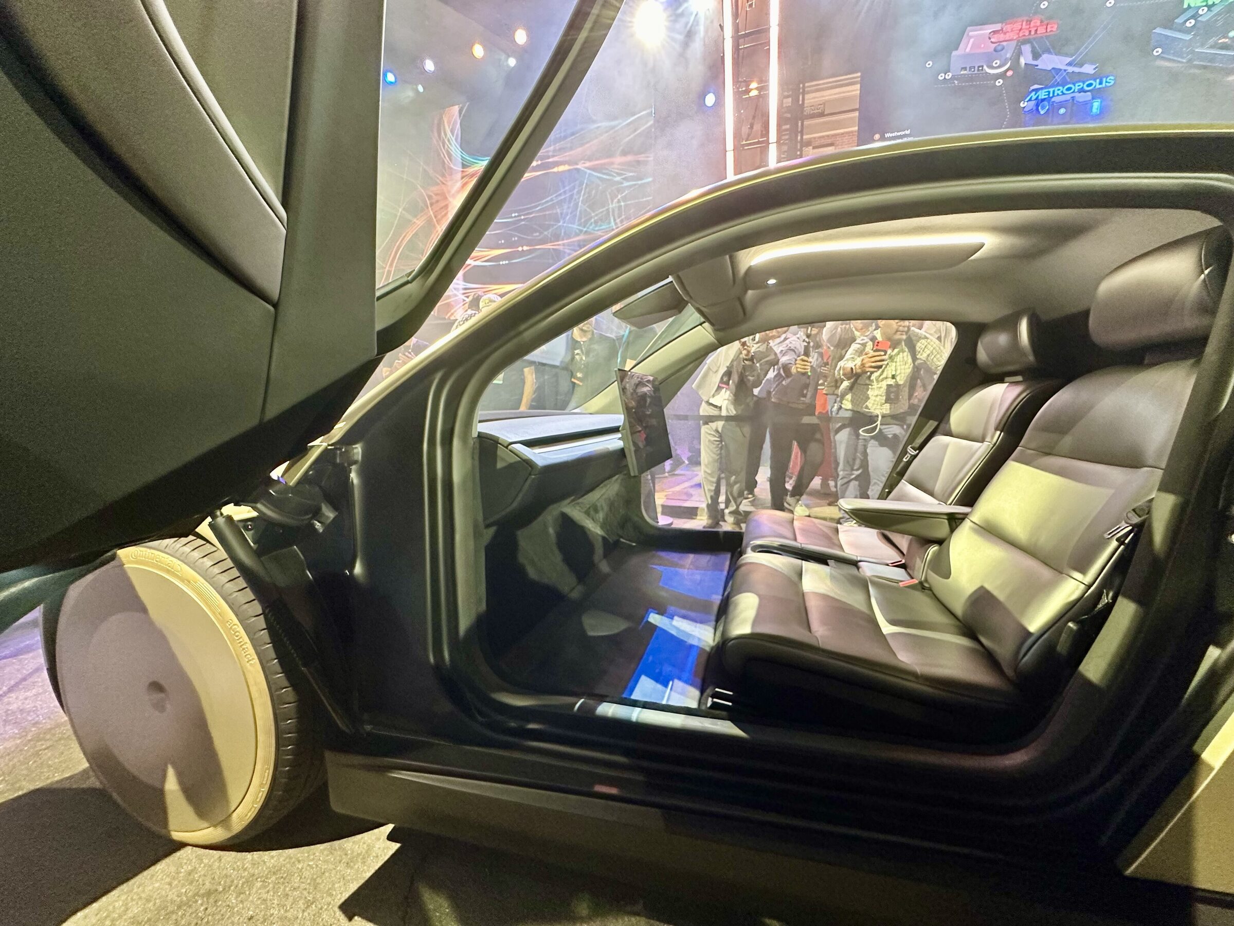 Inside a Tesla Cybercab: two seats, no steering wheel, butterfly door open.